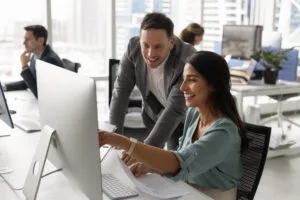 Happy manager and team leader discussing electronic content at computer