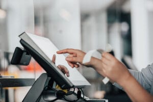 Young saleswoman doing process payment on touchscreen POS, count